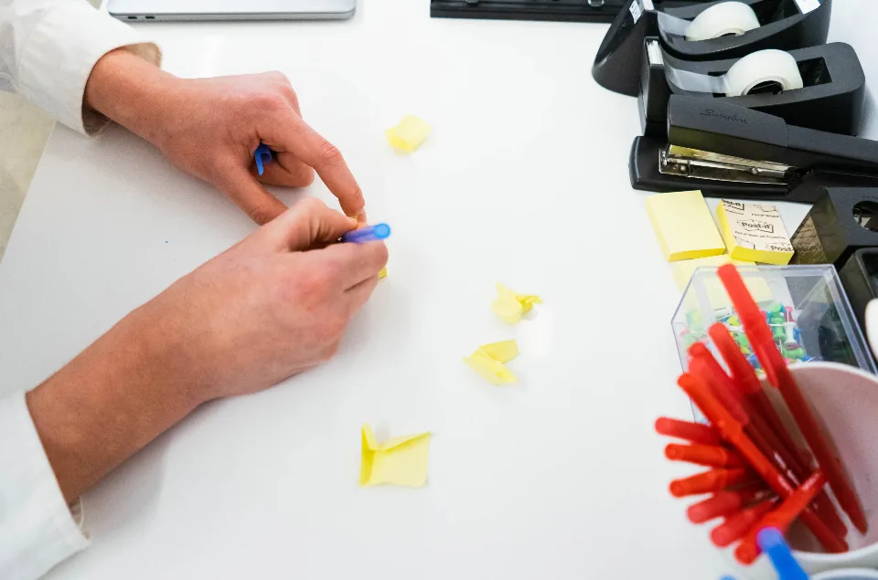 Hands arranging sticky notes during a creative training brainstorm