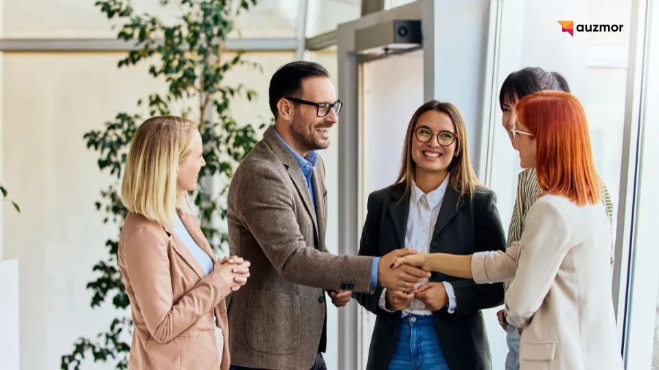 Colleagues smiling and shaking hands in a bright office with plants