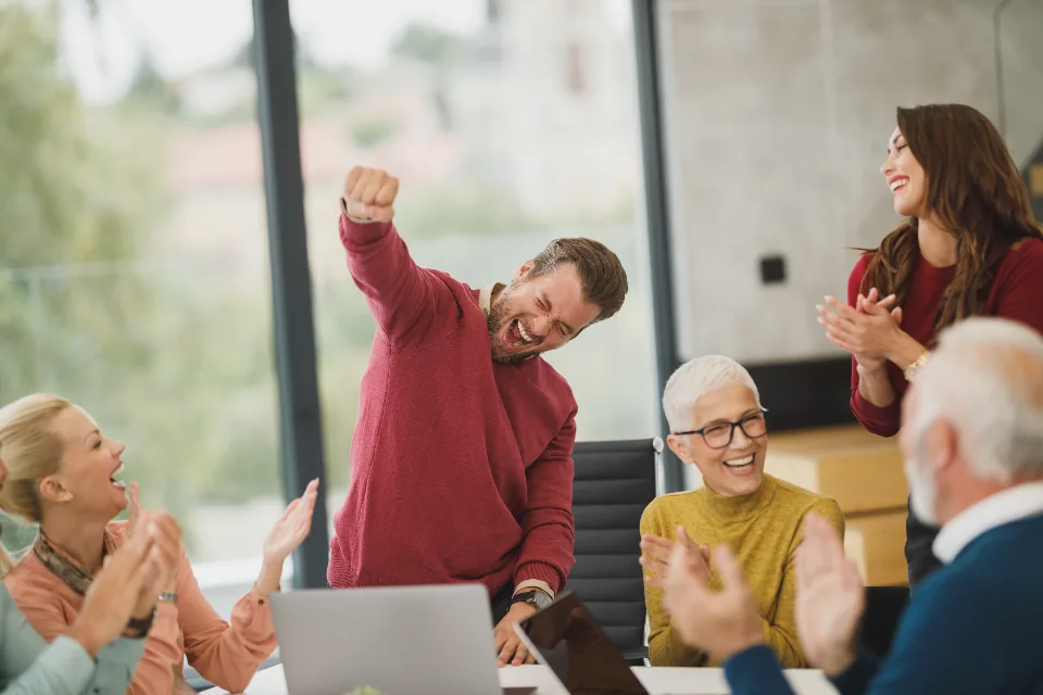 Team members applauding a colleague who is celebrating his recognition at work