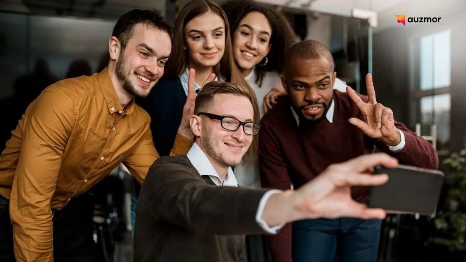 Five smiling team members posing together for a group selfie