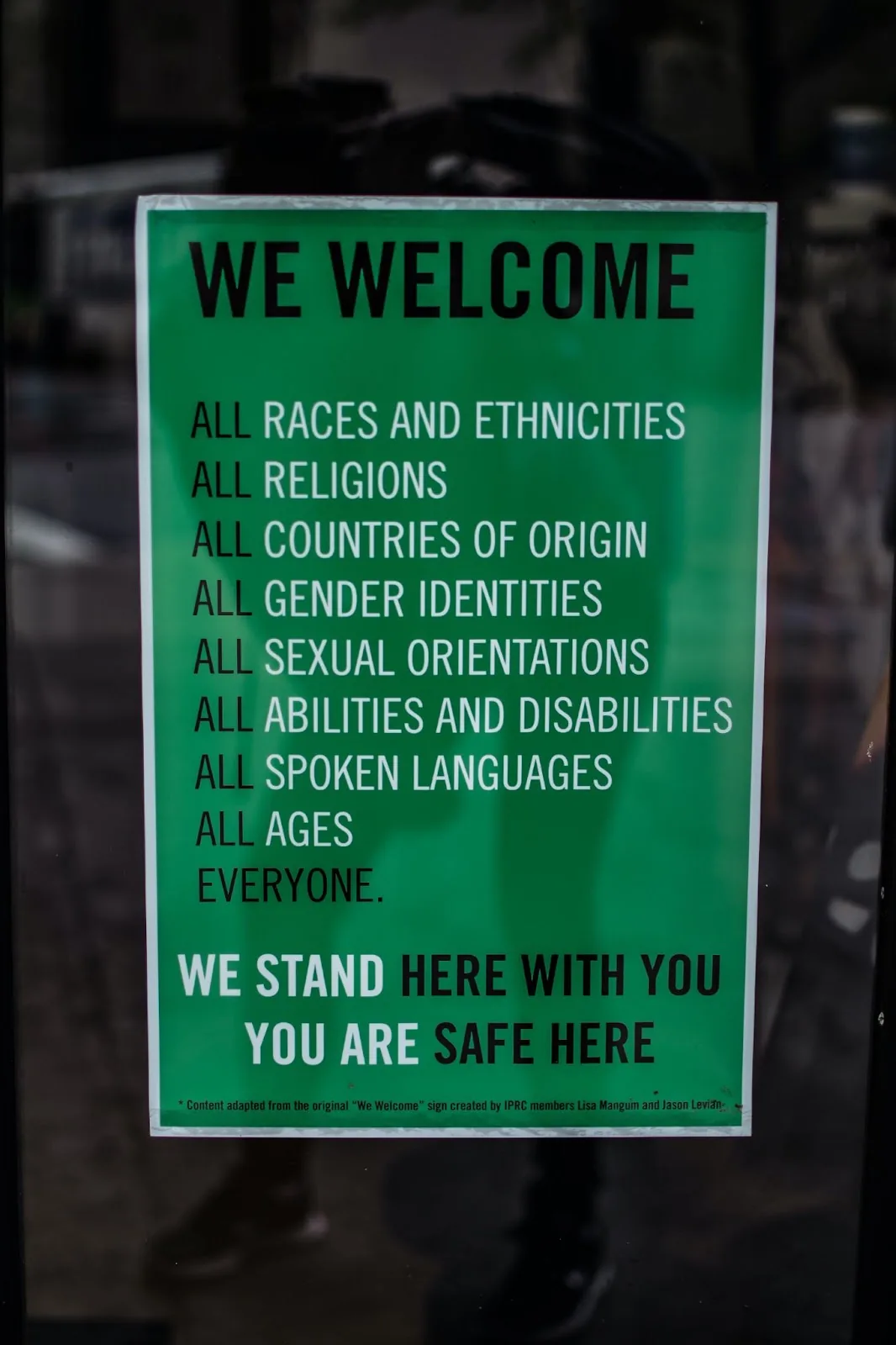 Green sign reading "We welcome all races, religions, countries of origin, gender identities, sexual orientations, abilities, languages and ages"