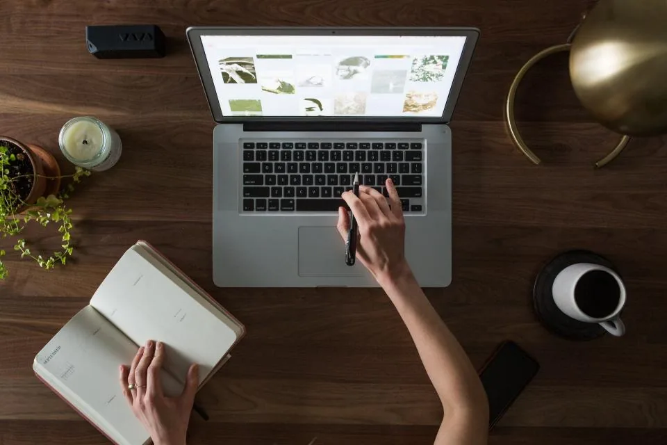 Employee attending a virtual training session on a laptop and taking notes